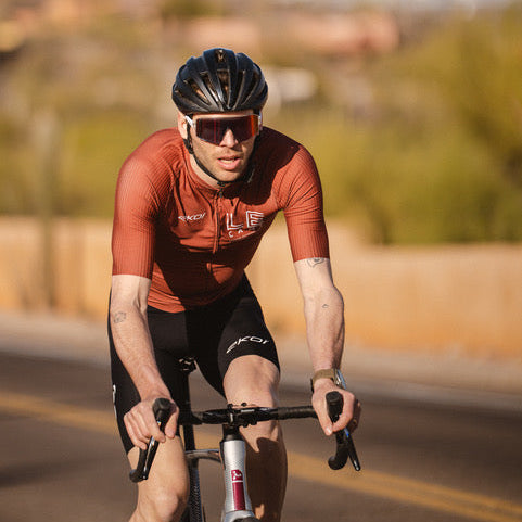 Cyclist in red jersey and black helmet riding on a road with blurred background