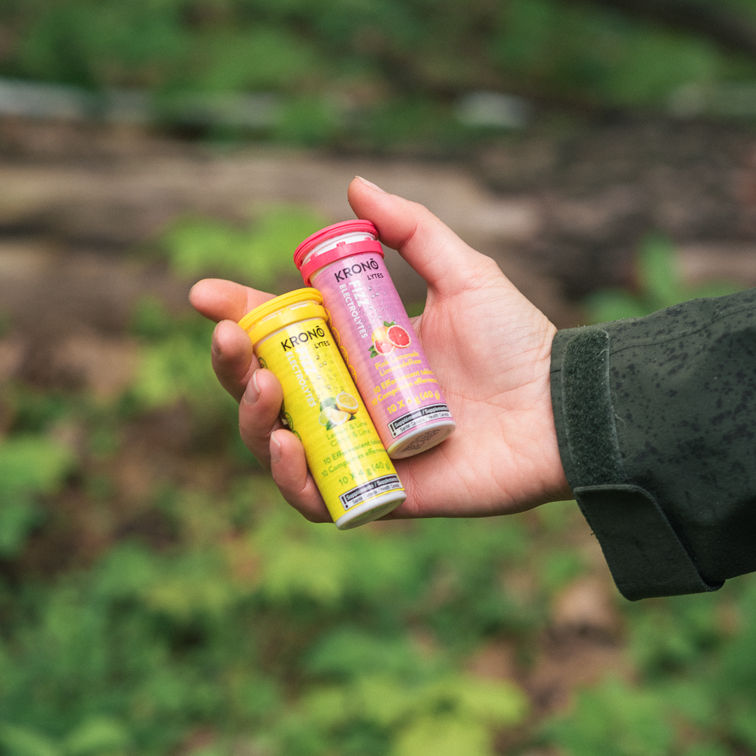 Hiker holding a Krono Nutrition pink lemonade and a lemon and lime effervescent tablets, on a rainy trail