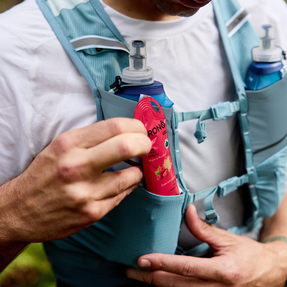 Runner taking out a Krono Nutrition maple and raspberry energy gel from his running vest, outdoors