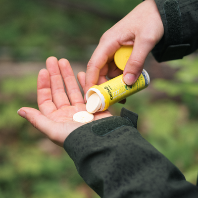 Hiker pouring Krono Nutrition lemon and lime effervescent tablets in his hand, on a rainy trail