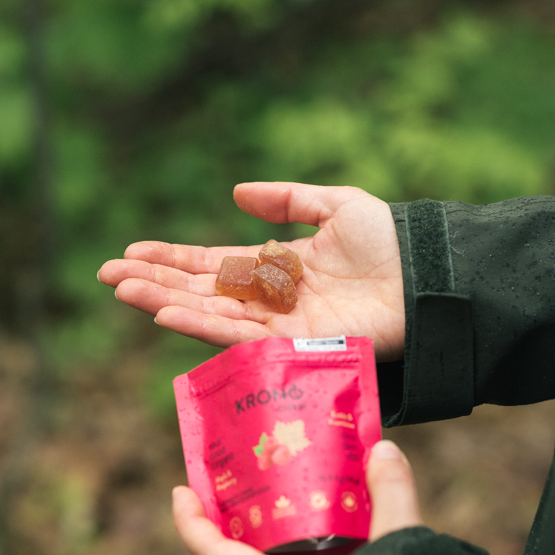 Hiker holding Krono Nutrition maple and raspberry energetic chews in his hand, on a rainy trail