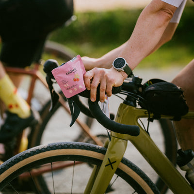 Cyclist holding Krono Nutrition maple and strawberry energetic chews, while riding his bike