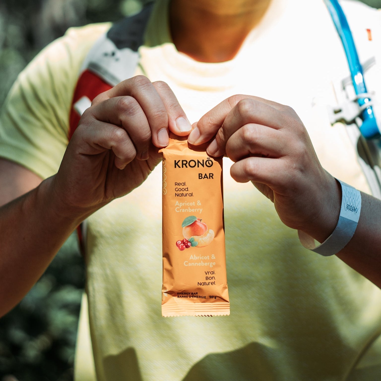Runner opening a Krono Nutrition apricot and cranberry energy bar, outdoors