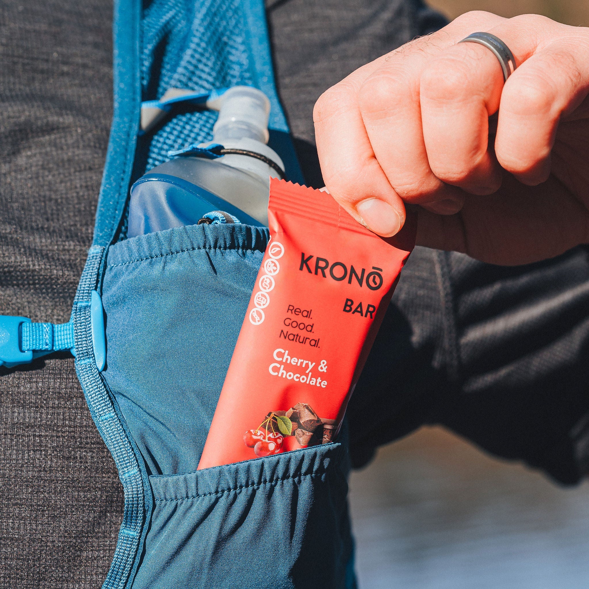 Runner taking out a Krono Nutrition cherry and chocolate energy bar from his running vest, outdoors