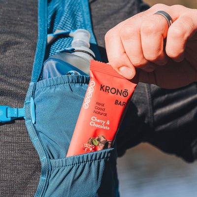 Runner taking out a Krono Nutrition cherry and chocolate energy bar from his running vest, outdoors