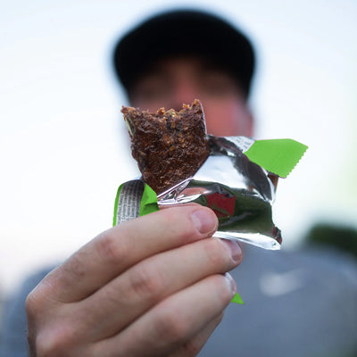Close-up of a Krono Nutrition maple and apple energy bar being held by a runner, outdoors