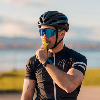 Cyclist drinking a Krono Nutrition citrus fruits energy gel, with a blurry outdoors background