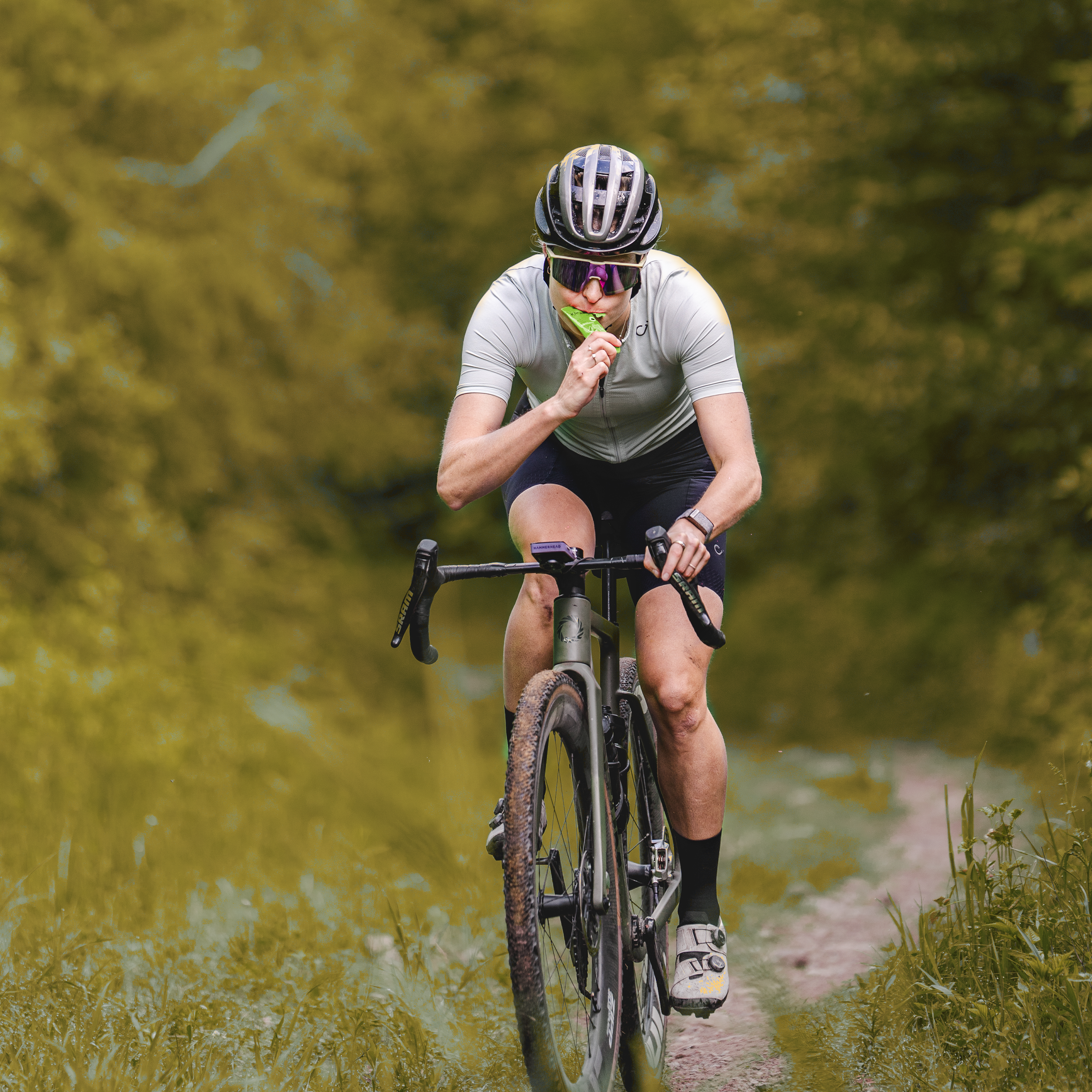 Cyclist drinking Krono Nutrition maple and apple energy gel, while cycling on a trail