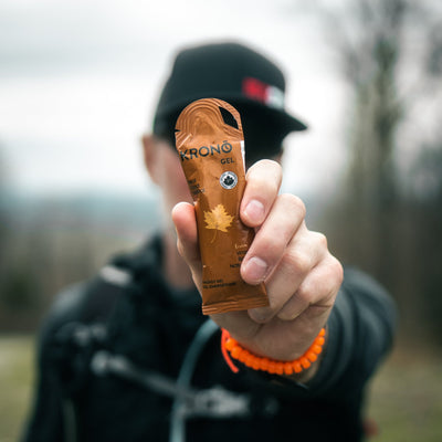 Close-up of runner holding Krono Nutrition maple energy gel, outdoors