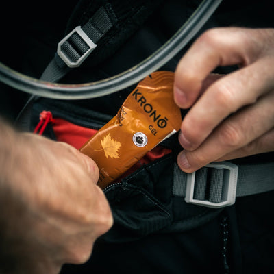 Runner taking out a Krono Nutrition maple energy gel from his running vest, outdoors
