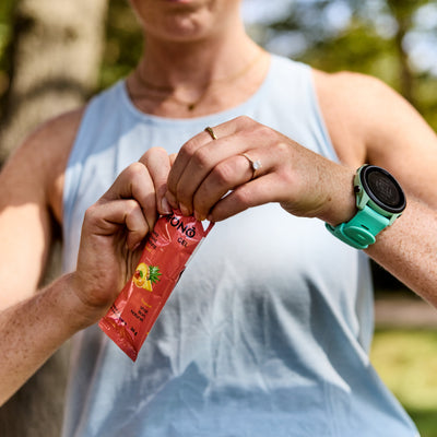 Close-up of runner opening Krono Nutrition tropical energy gel, outdoors