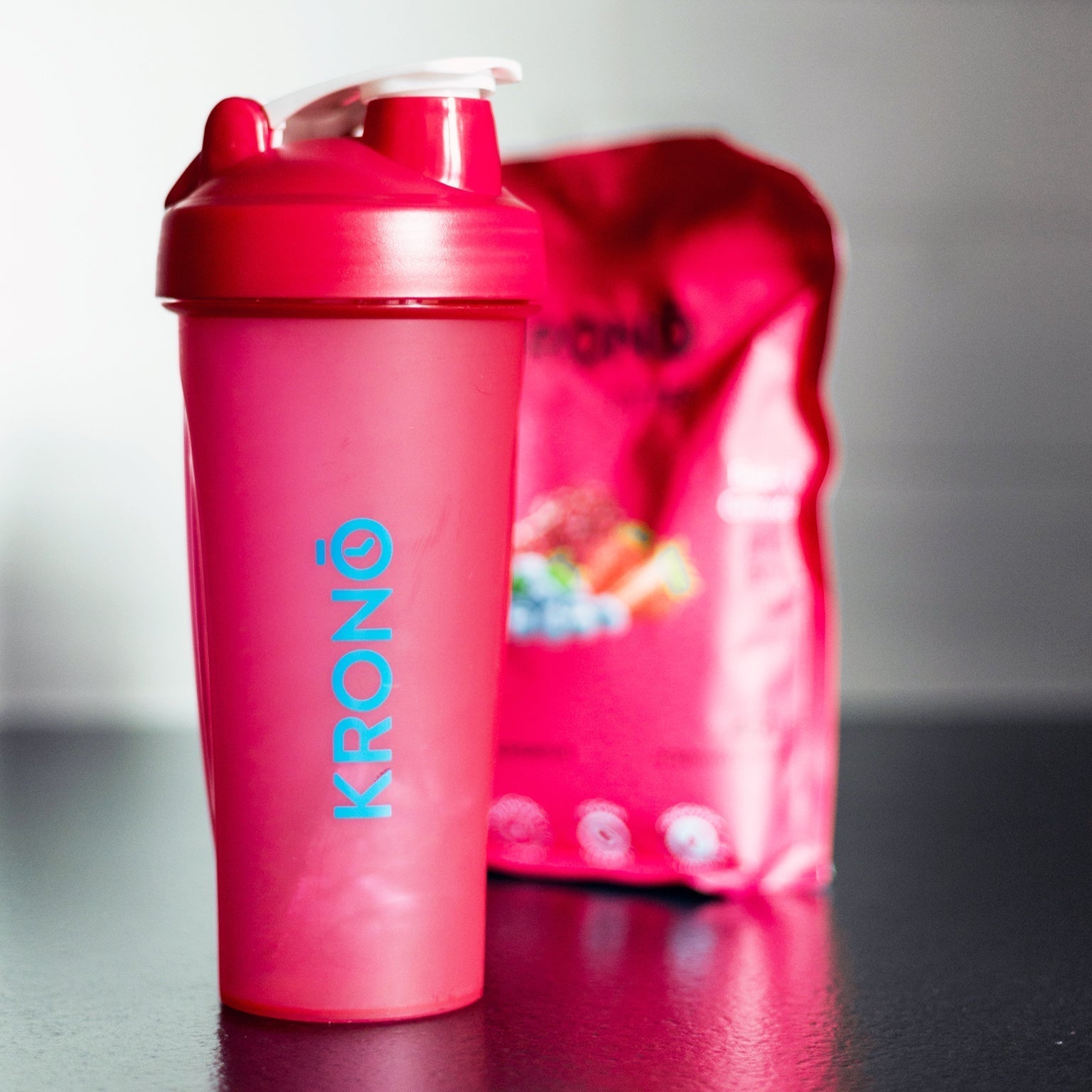 Krono Nutrition berries mixing bottle, on a countertop, in front of a Krono Nutrition berries sport drink mix
