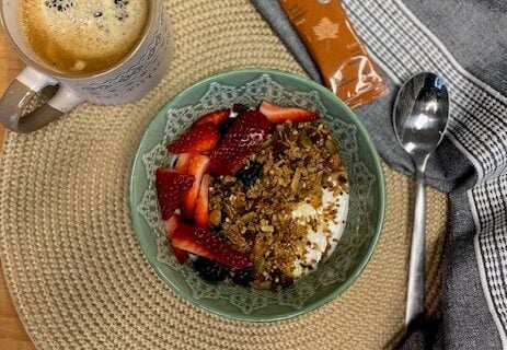 Bol granola, café et Krono Gel à l'érable, sur un napperon rond et accompagnés d'une cuillère et d'une serviette de table.